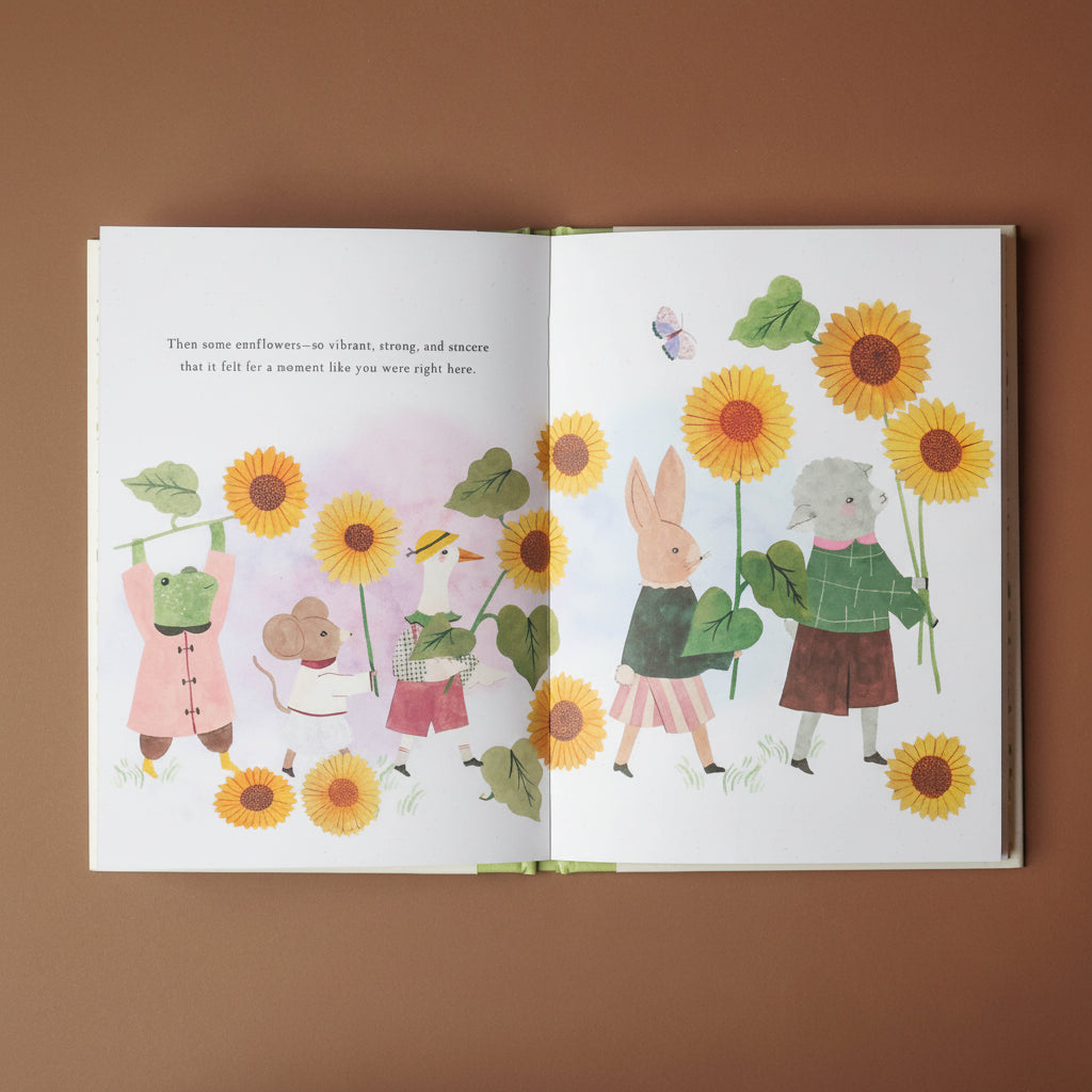 Illustrated book open to a page with characters holding sunflowers on a brown background