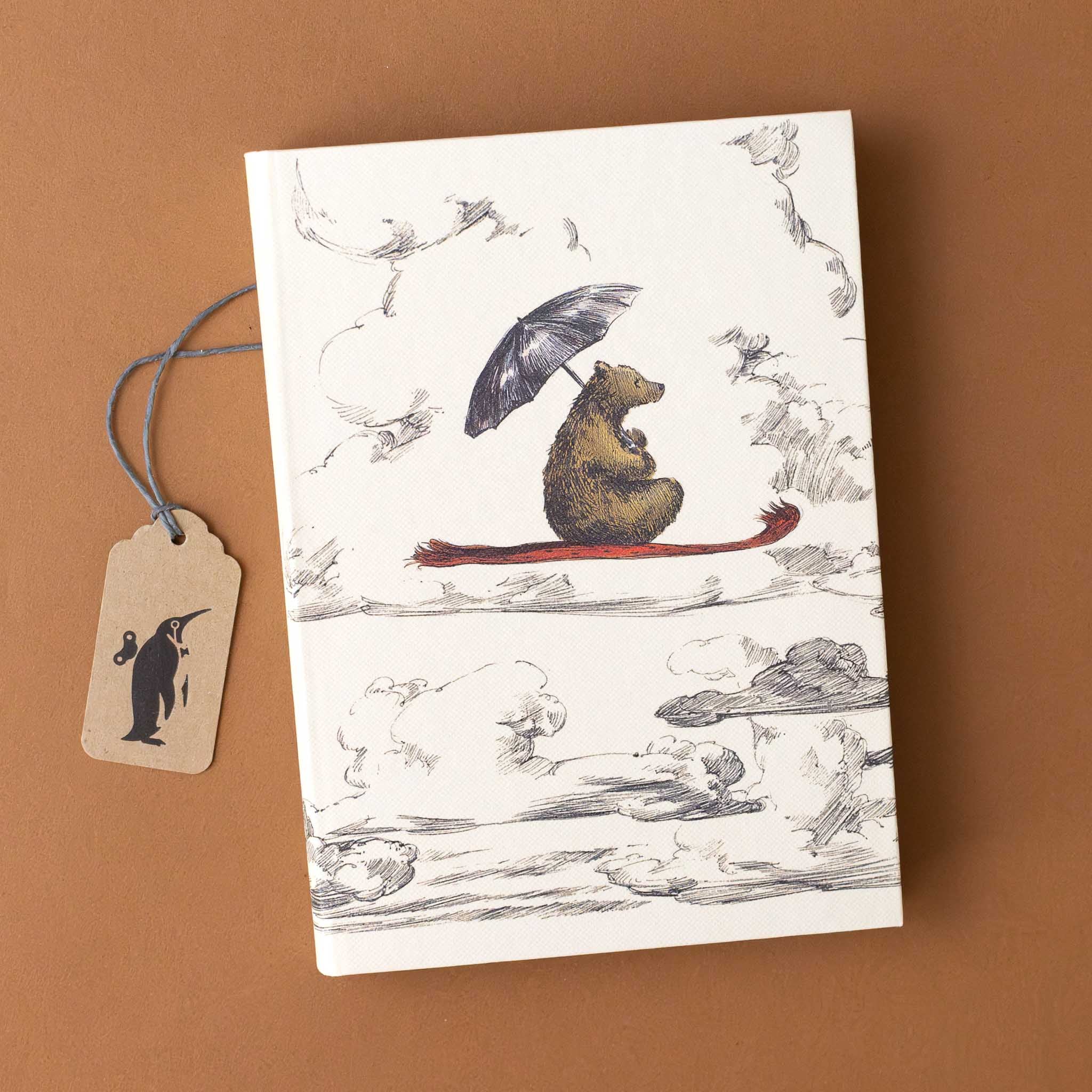 illustrated-journal-flying-bear-on-a-red-carpet-holding-a-black-umbrella-through-the-clouds-cover