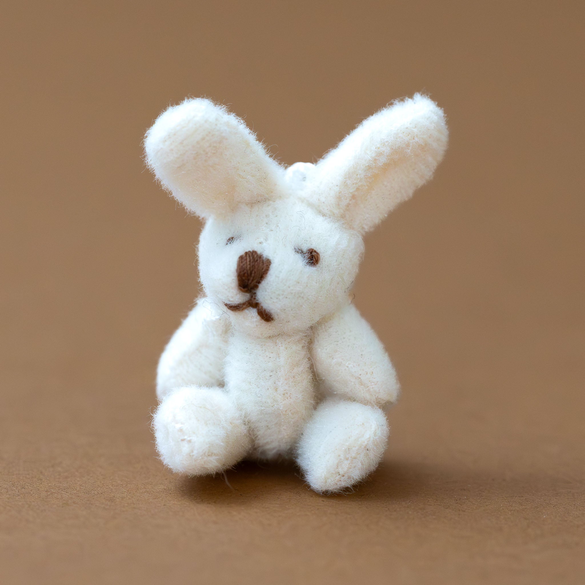 itty-bitty-bunny--coconut Small white stuffed bunny toy on a brown background