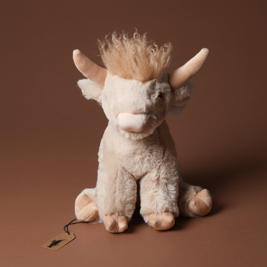 Plush toy lad-the-highland-cow with brown hair on a brown background