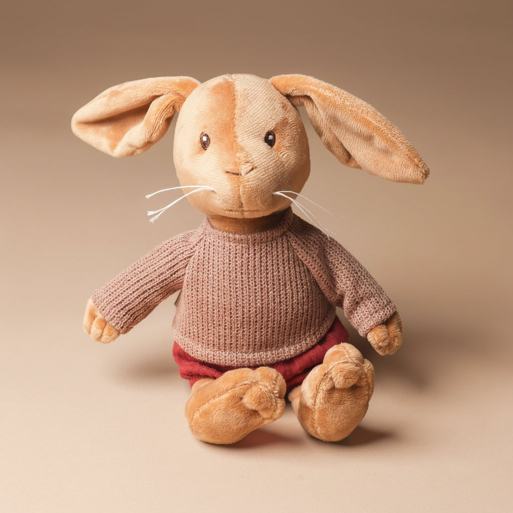 Stuffed lenny-the-musical-rabbit toy wearing a knitted sweater and red pants on a beige background