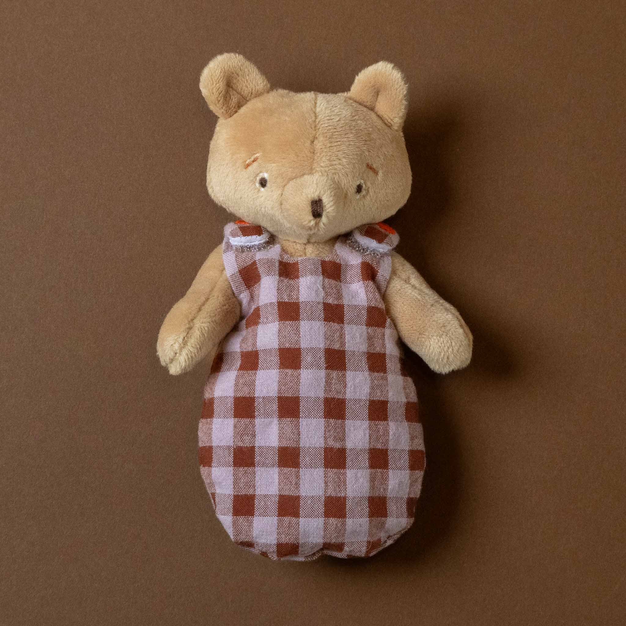les-minouchkas-bebe-emile-the-bear Stuffed teddy bear wearing a red and white checkered outfit on a brown background