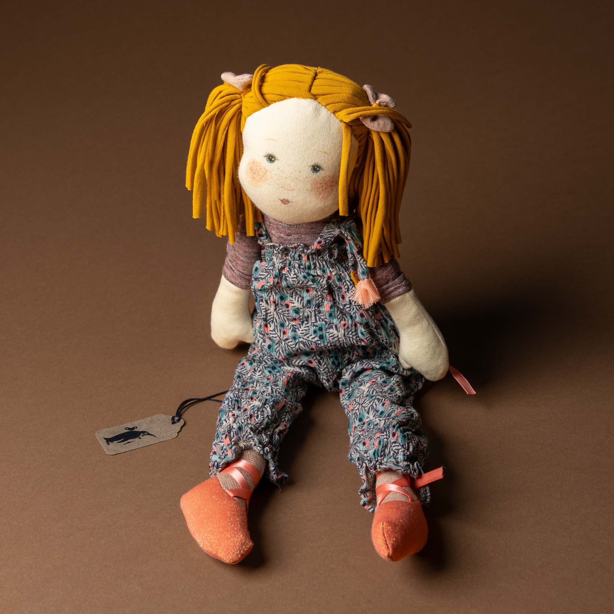 les-rosalies-rag-doll-violette Stuffed doll with yellow hair and floral overalls on a brown background