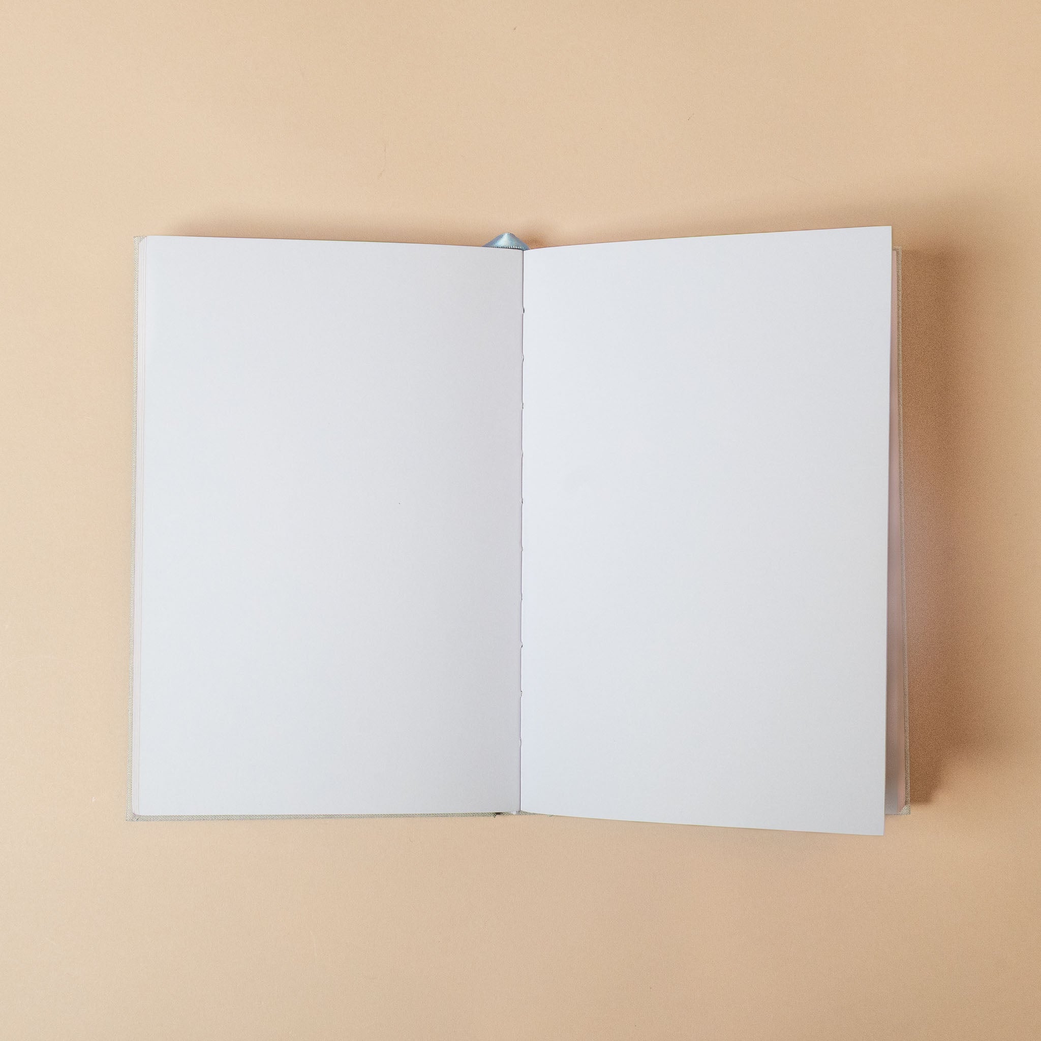 linen-embossed-sketchbook-green-floral Open book with blank pages on a beige background