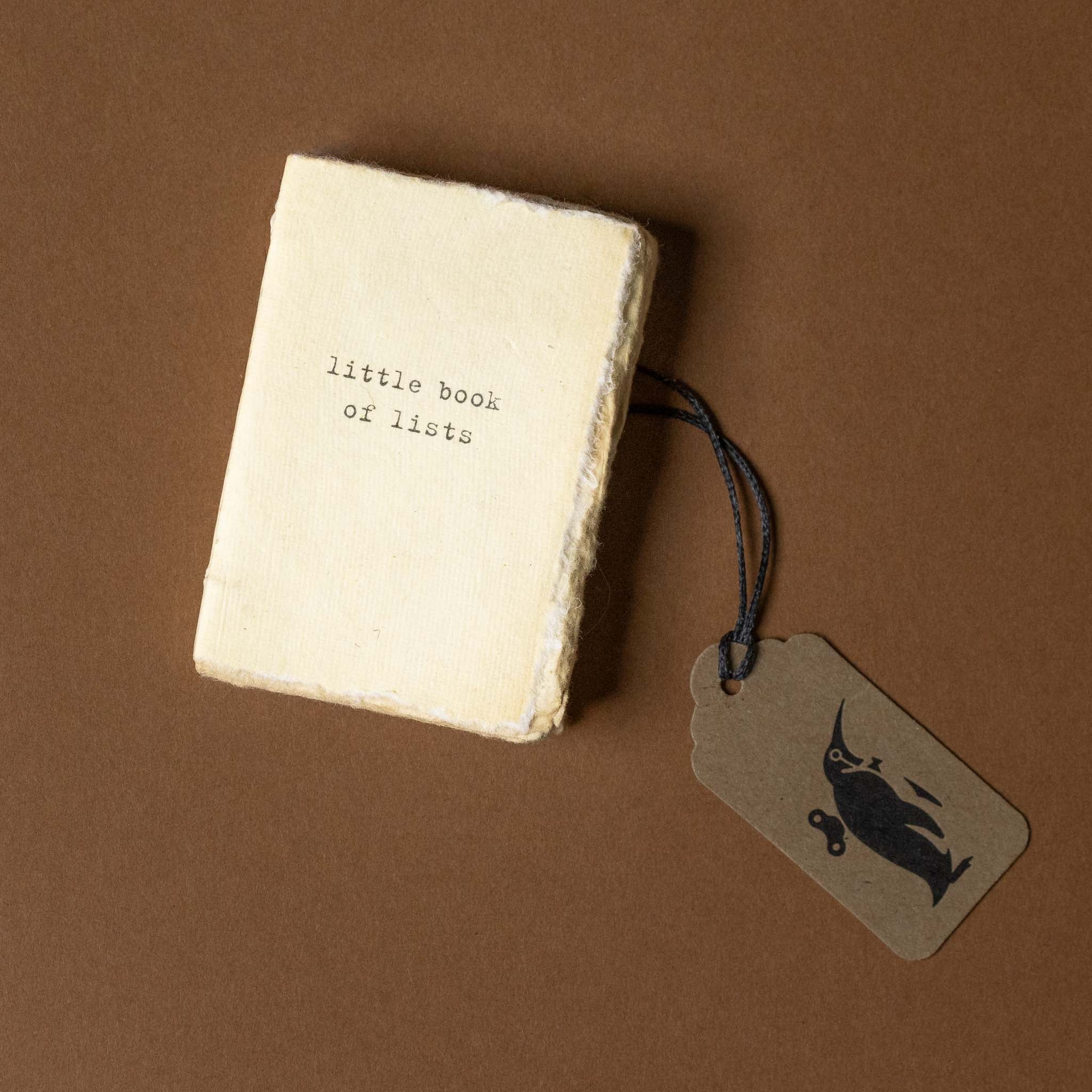 Small book titled 'little book of lists' with a tag on a brown background