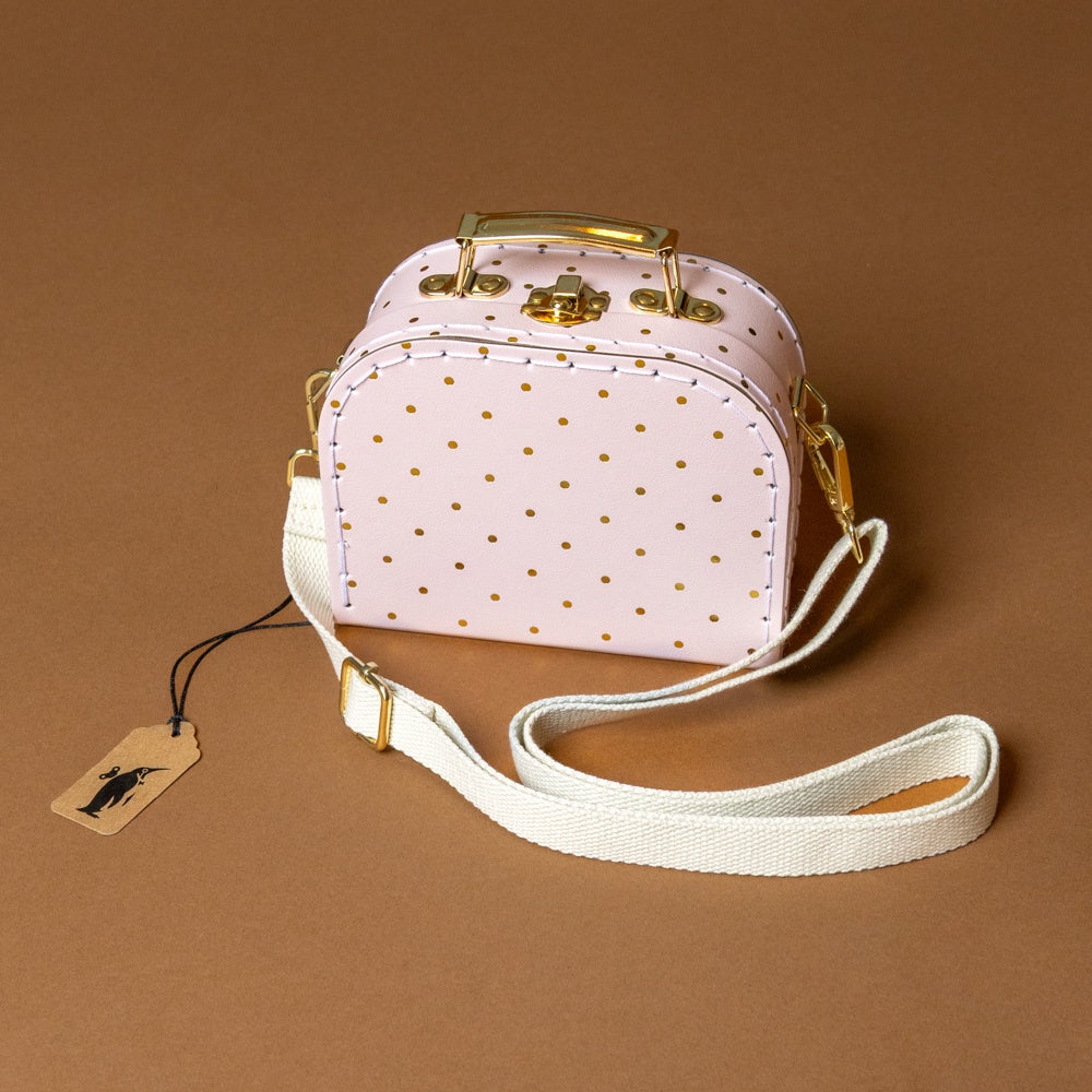 little-cross-body-case-pink-gold polka dot handbag with gold accents on a brown background