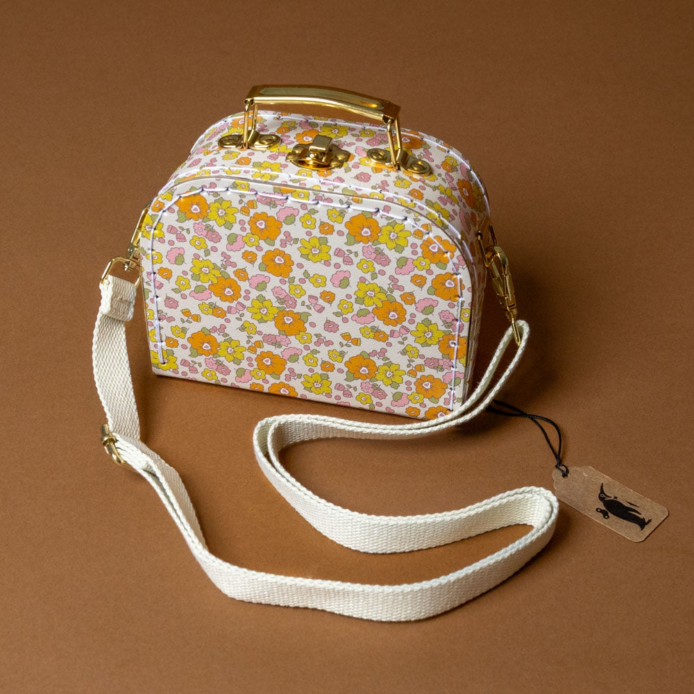 Floral patterned little-cross-body-case-sweet-marigold with a white strap on a brown background