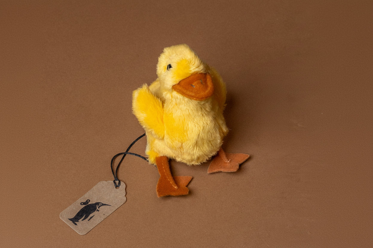 little-duck-chick-finger-puppet Yellow plush duck with a tag on a brown background