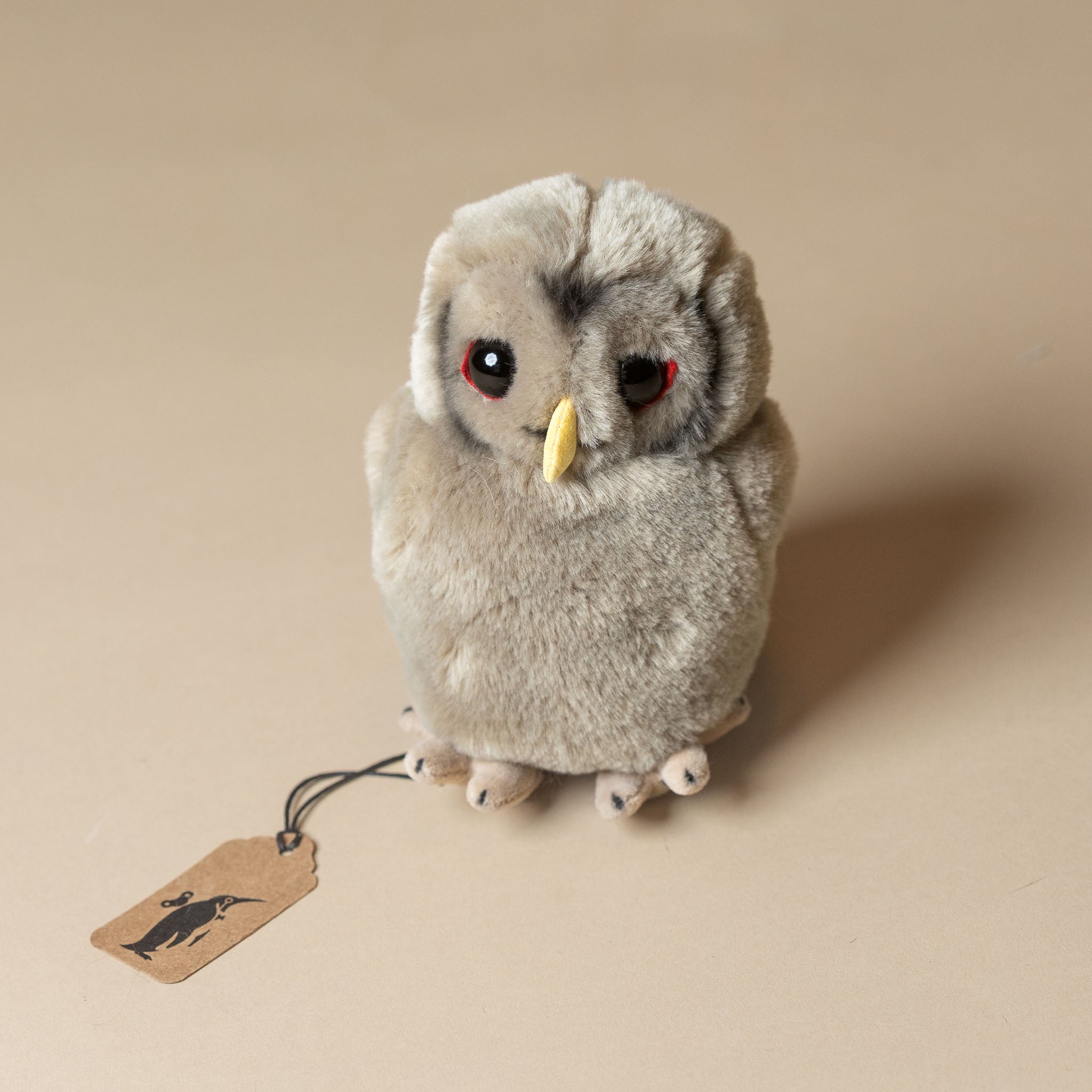 little-grey-owlet Plush owl toy with a tag on a beige background