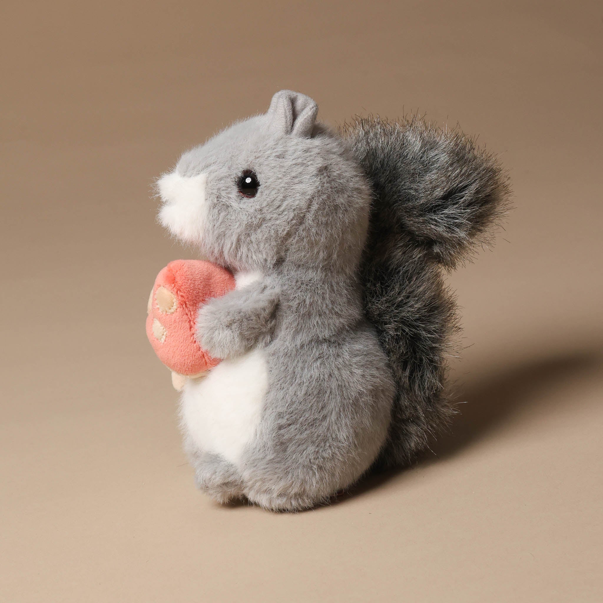 Plush toy little-grey-squirrel-with-toadstool on a beige background