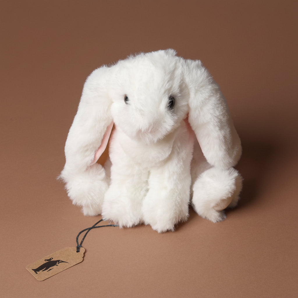 White plush little-lottie-bunny-white toy with a tag on a brown background
