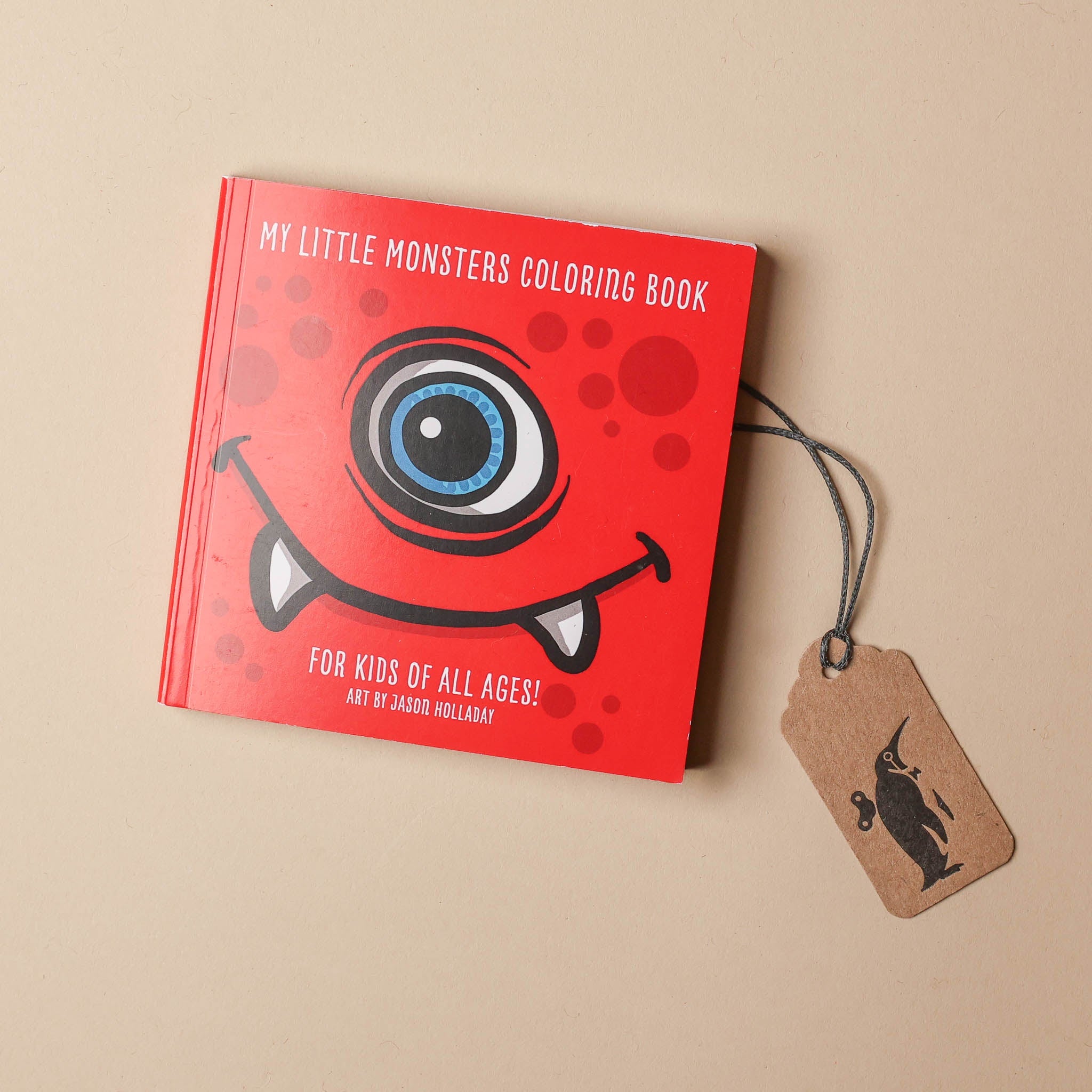 Red coloring book titled 'My Little Monsters Coloring Book' with a tag on a beige background