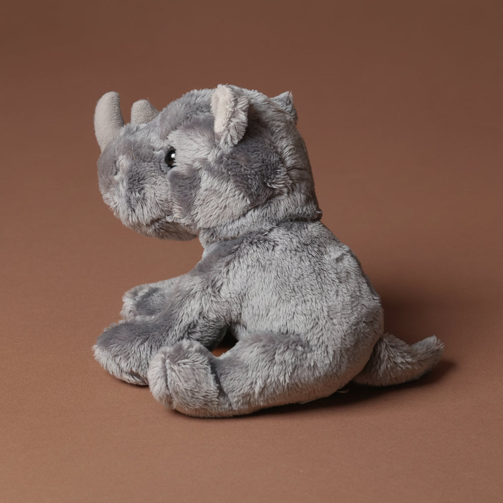 Plush little-rhino-cub toy on a brown background
