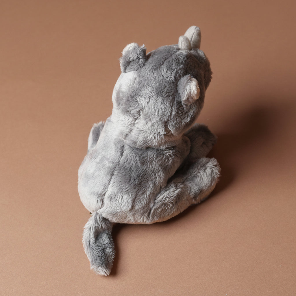 Plush little-rhino-cub toy on a brown background