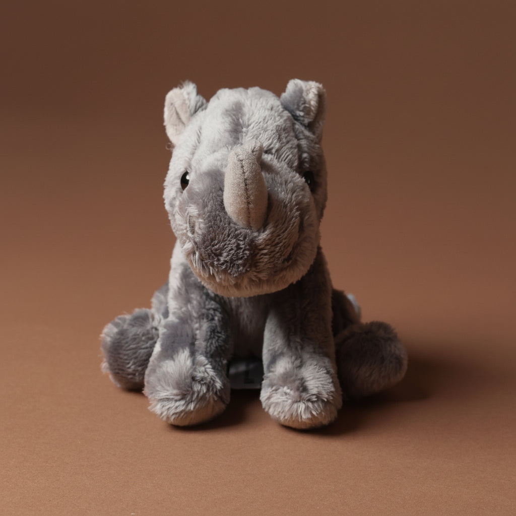 Plush little-rhino-cub toy on a brown background