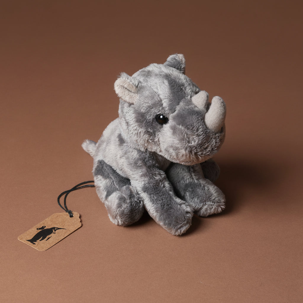 Plush little-rhino-cub toy on a brown background