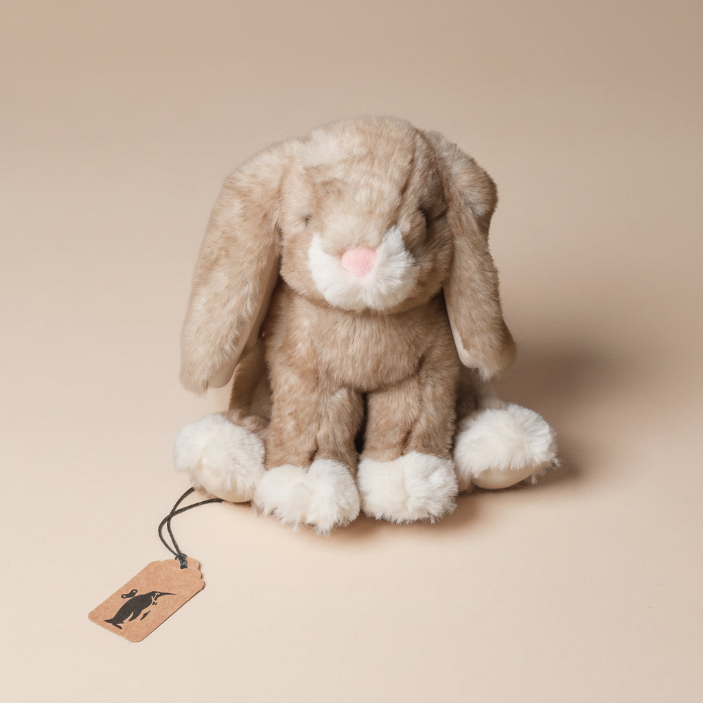 Plush little-white-foot-artie-bunny-sitting toy with a tag on a beige background