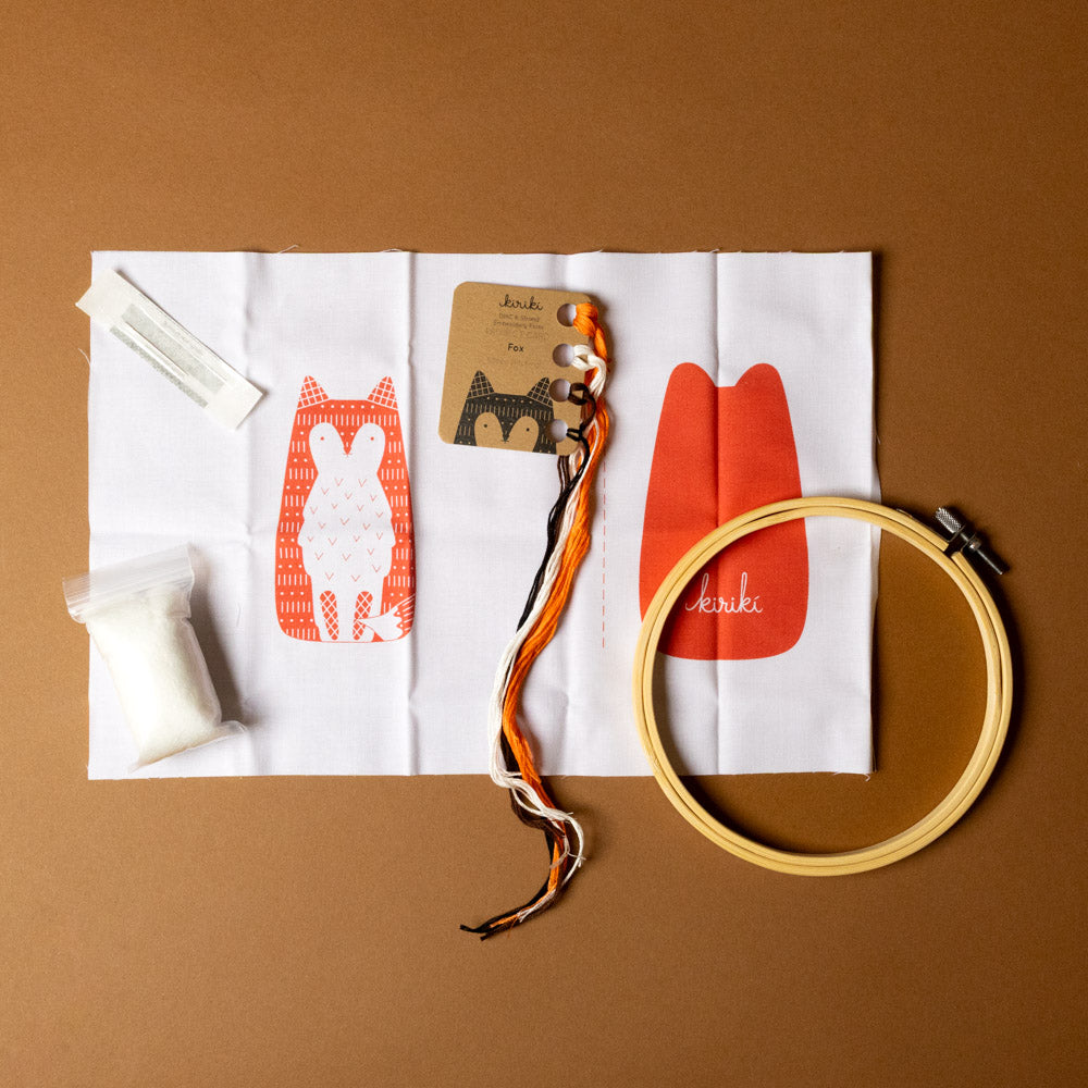 make-your-own-embroidered-animal-kit--fox Embroidery hoop, thread, and fabric with fox design on a brown background