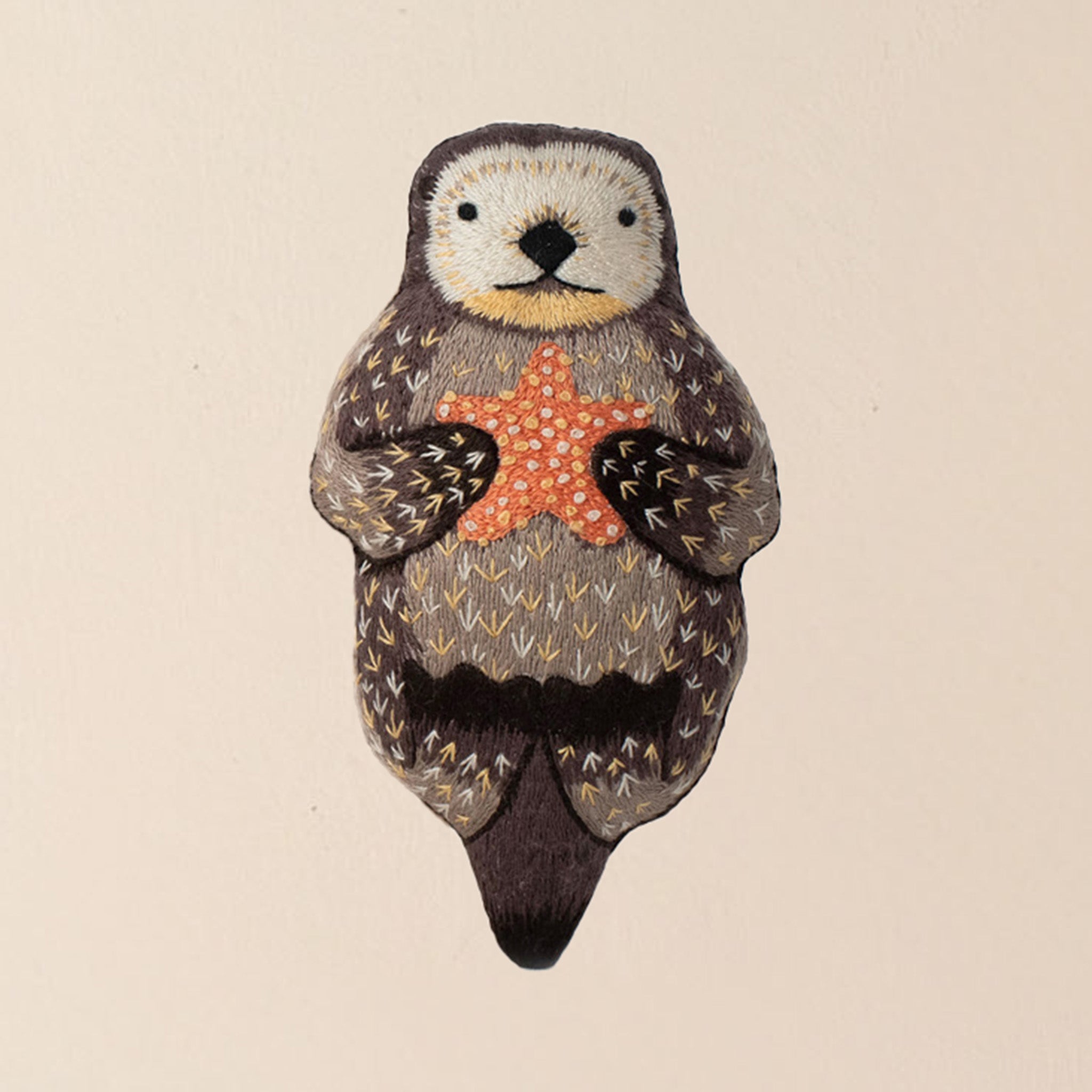 make-your-own-embroidered-animal-kit-otter-finished-brown-plushie-holding-an-orange-starfish