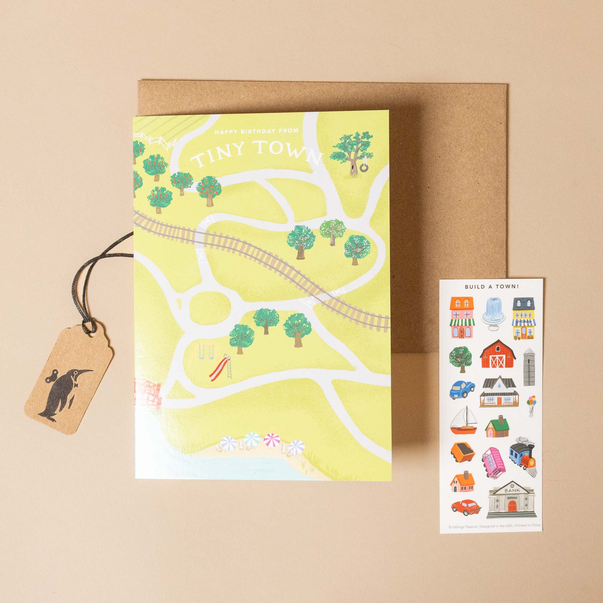 Map of a town with trees and roads, a brown envelope, a tag, and a sticker sheet on a beige background.