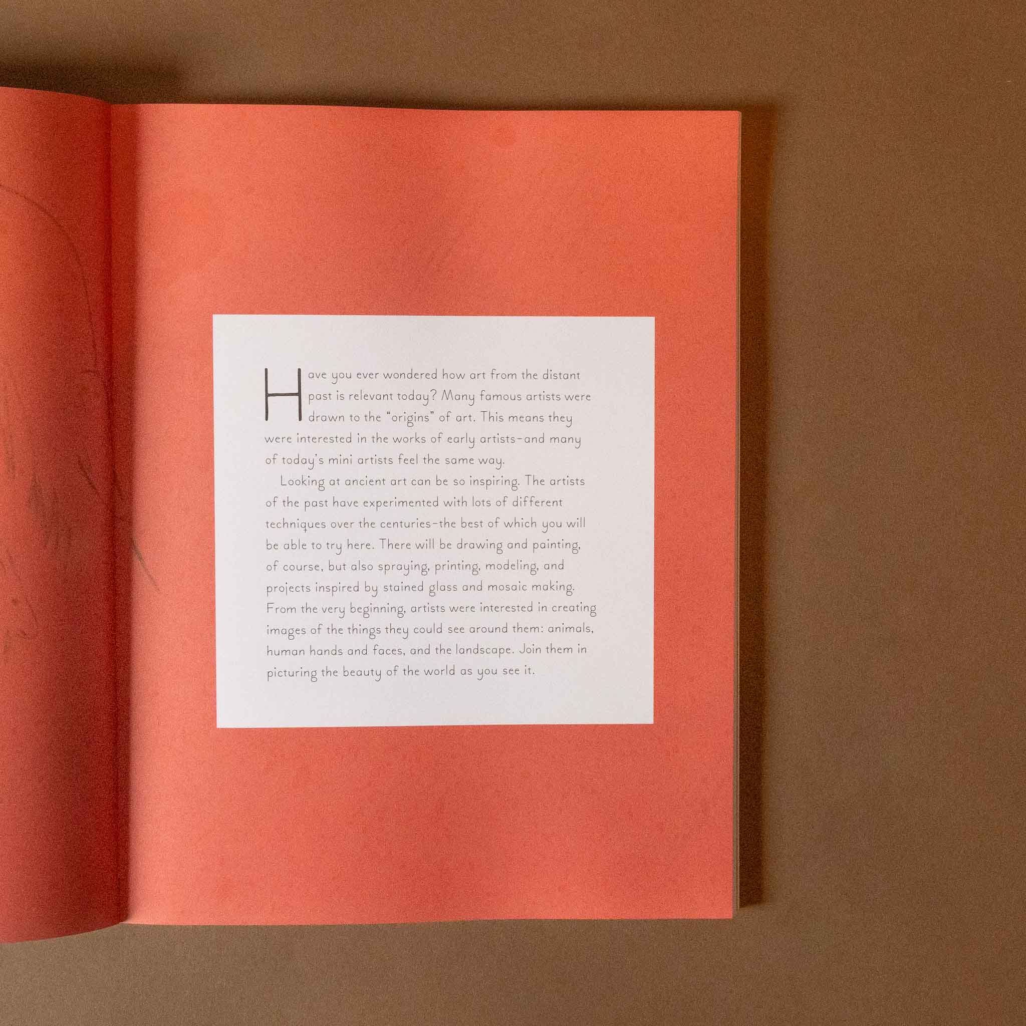 Open mini-artists-activity-book with a white page featuring text on a red background