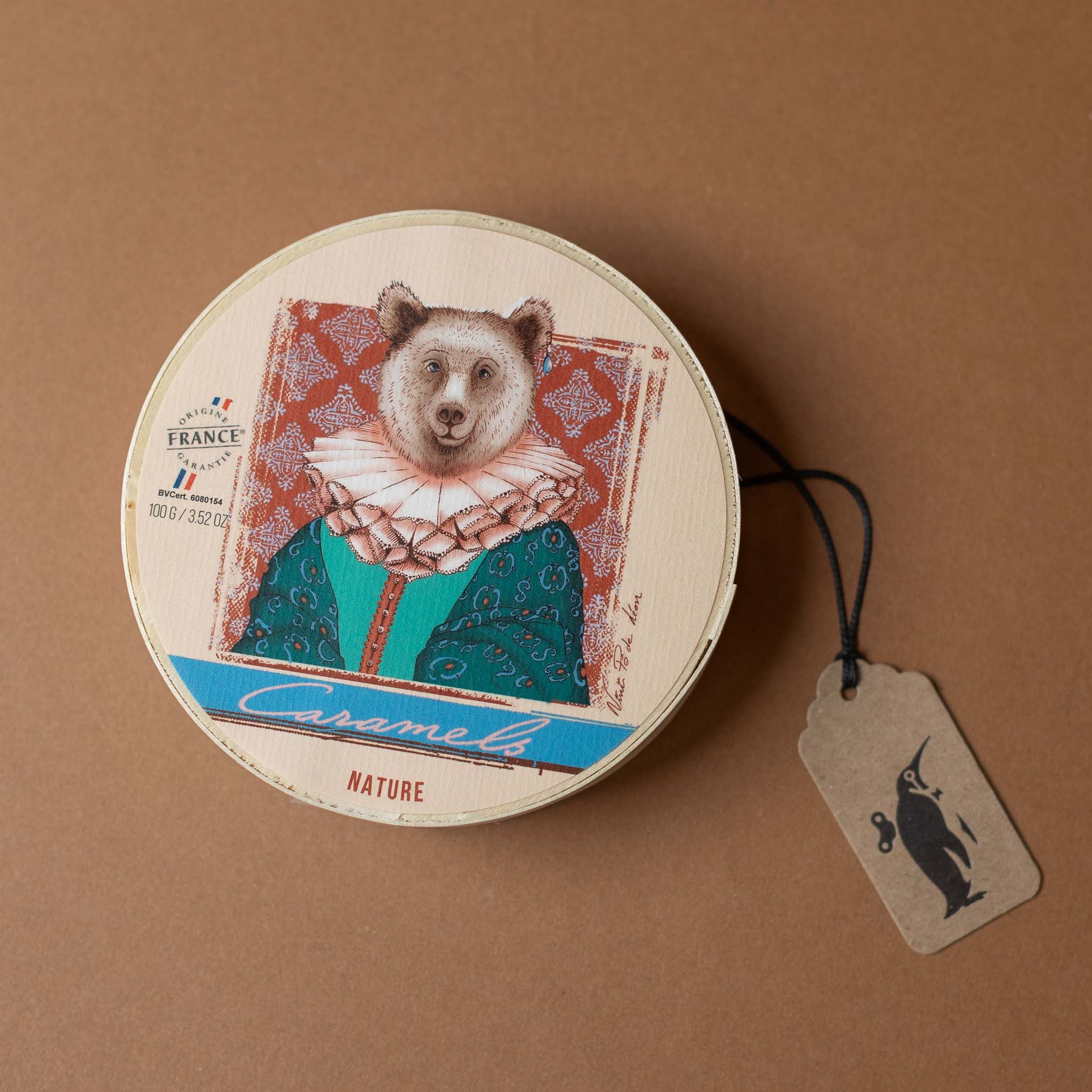 mon-pari-gourmand-caramels-with-chip-wood-box Round product packaging with a bear illustration on a brown background