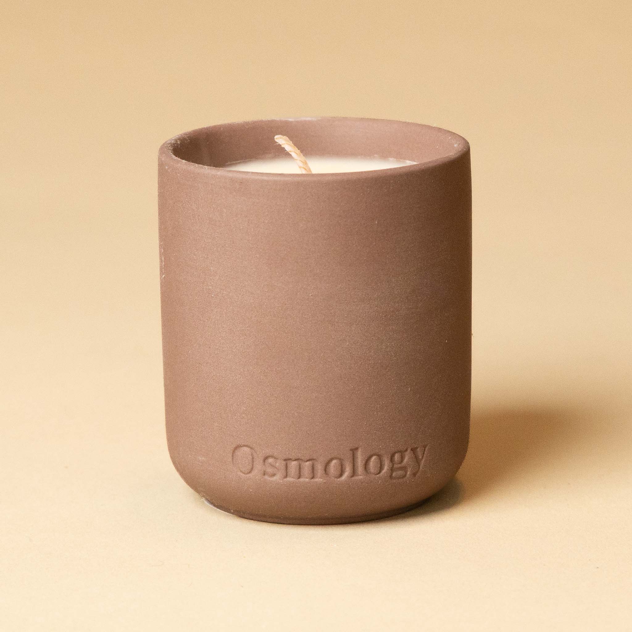 Ceramic candle in a mauve holder moroccan-rose-votive-candle on a beige background
