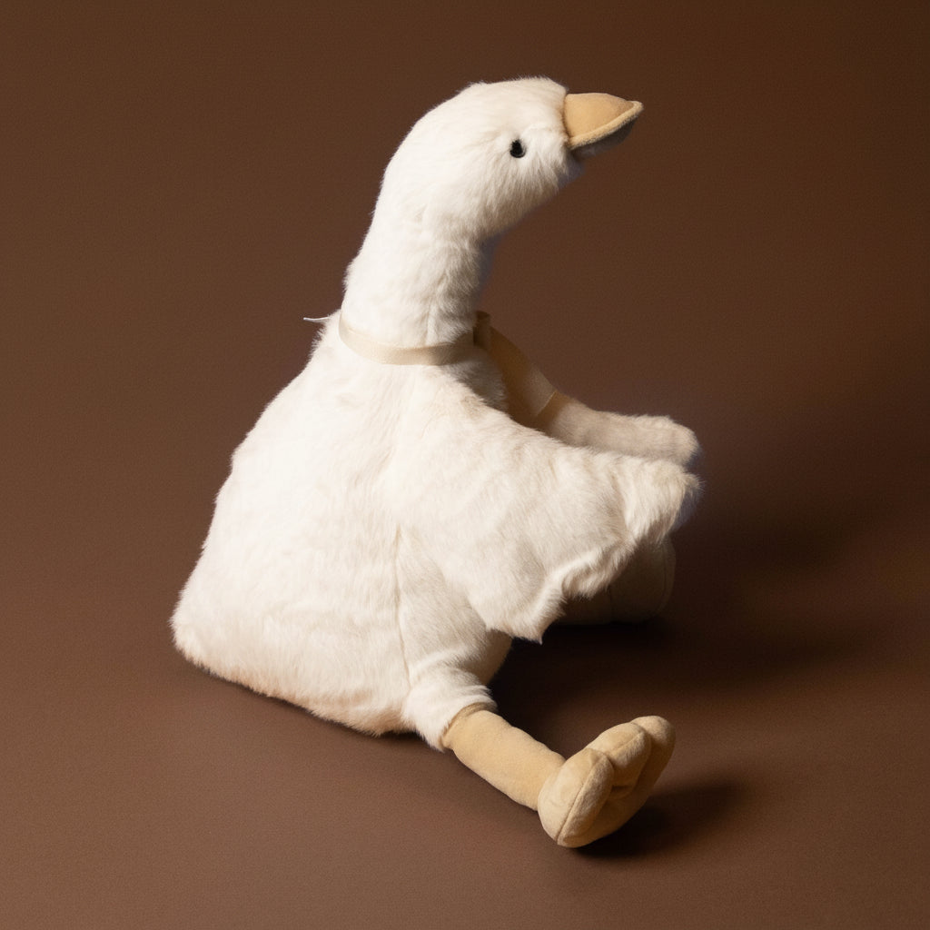 White plush duck toy with a bow on a brown background