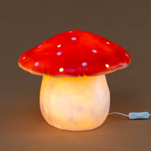 Load image into Gallery viewer, lit-lamp-soft-glow-of-cream-base-and-red-mushroom-top-with-white-spots-and-openings-to-create-light-dapplings-in-room