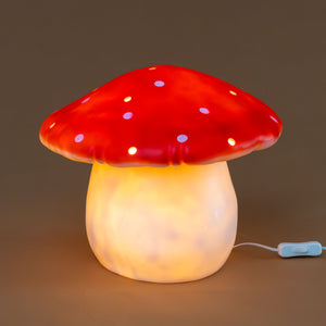 lit-lamp-soft-glow-of-cream-base-and-red-mushroom-top-with-white-spots-and-openings-to-create-light-dapplings-in-room