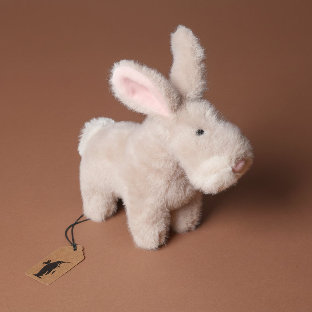 muzzle-bernadette-bunny-small Plush rabbit toy with a tag on a brown background