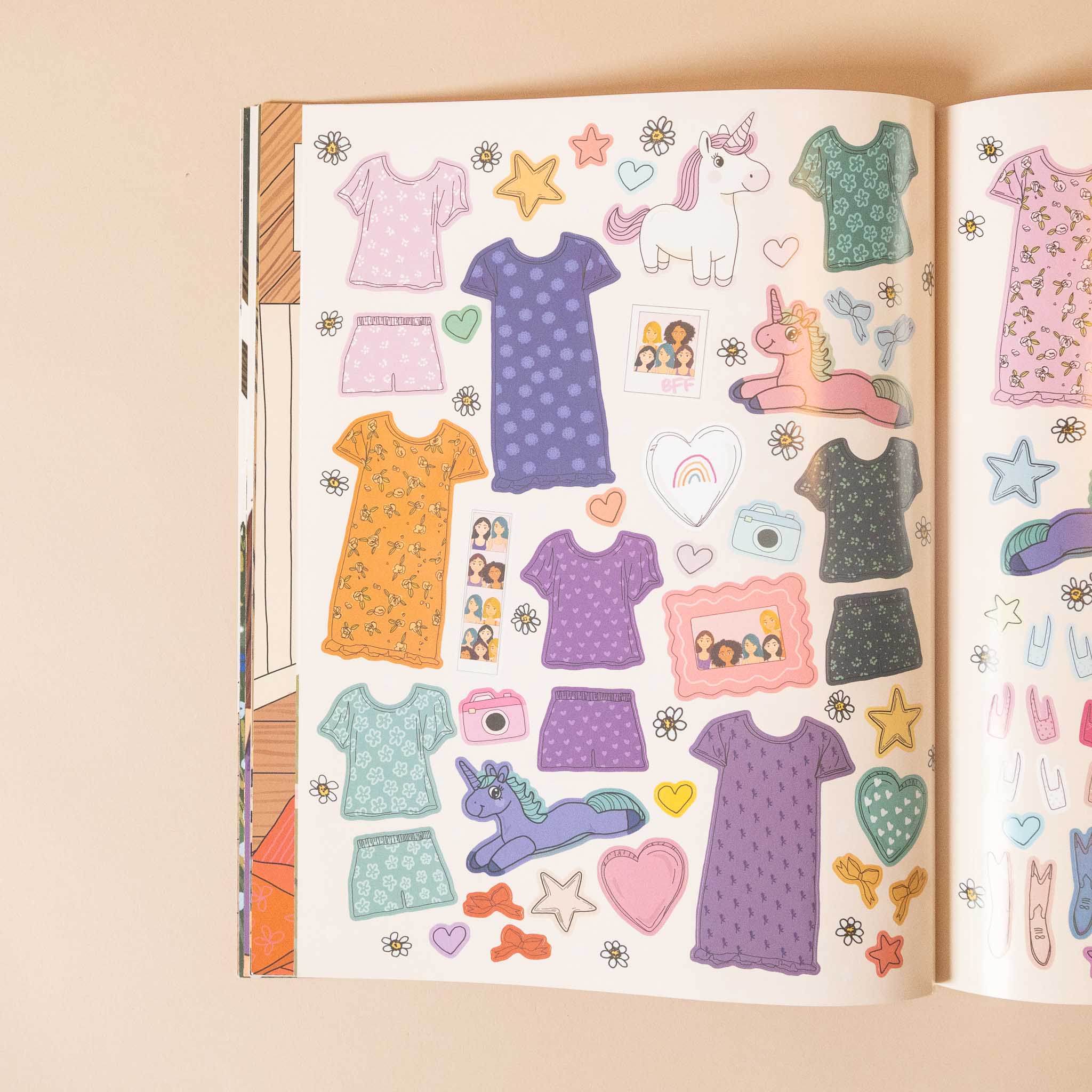my-sticker-storybook-fairies-and-unicornsOpen book with colorful clothing and accessory stickers on a beige background