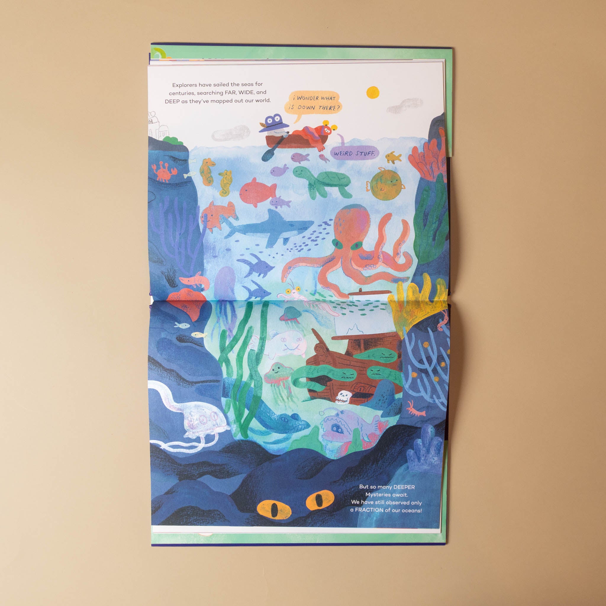 An open illustrated book or booklet laid flat on a beige surface, showing a colorful underwater scene with sea life, coral, and text panels.