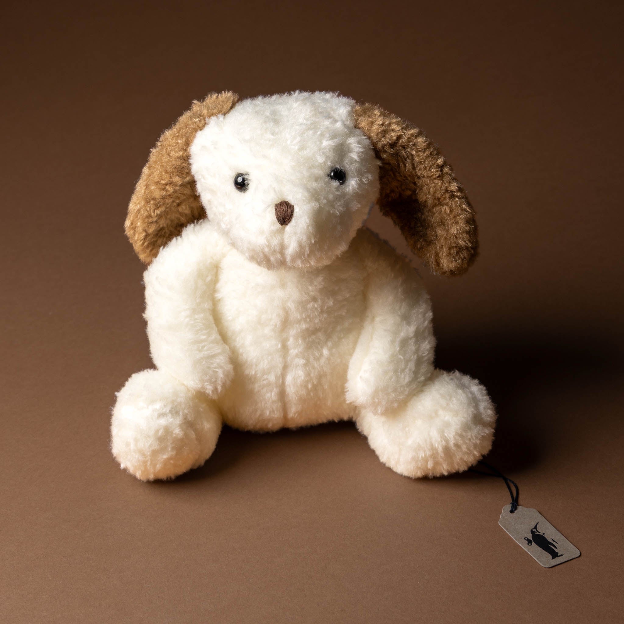 nafi-puppy-grande Plush dog toy with a tag on a brown background