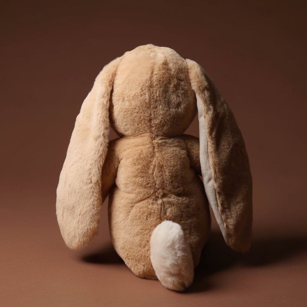 Plush nibbles-bunny-almond-medium toy on a brown background