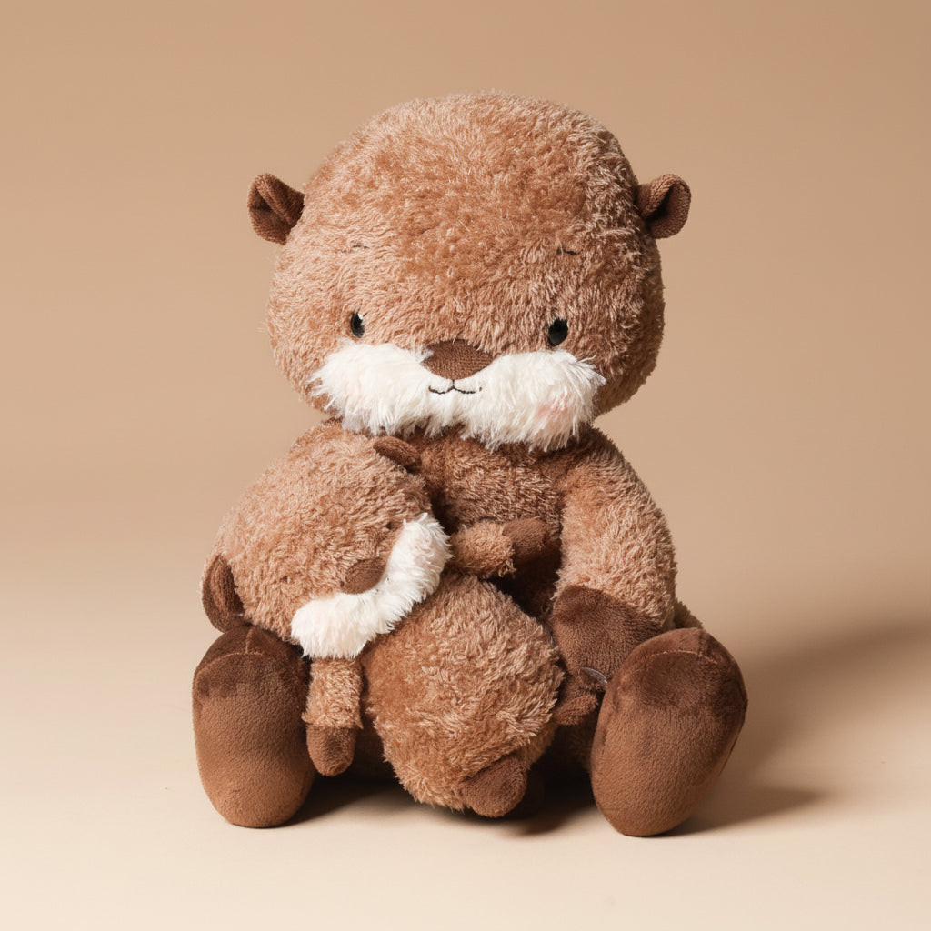 Plush toy ollie-otter-and-baby sitting on a beige background