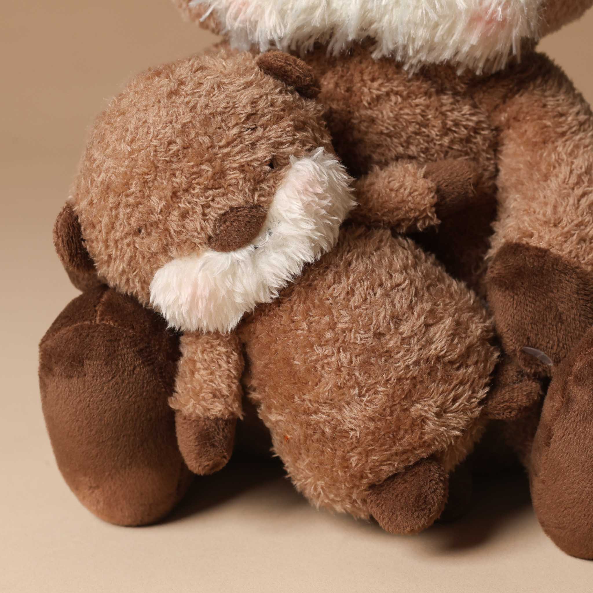 Plush toy ollie-otter-and-baby sitting on a beige background