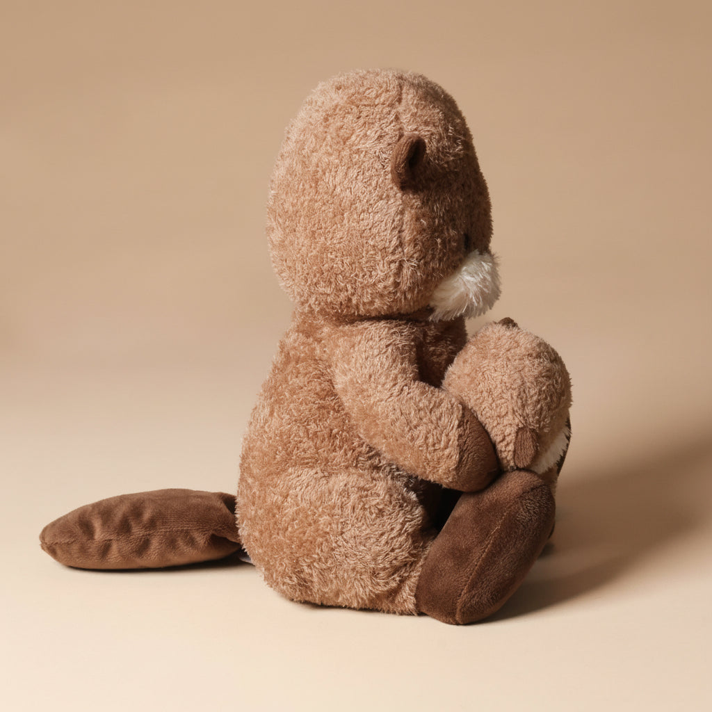 Plush toy ollie-otter-and-baby sitting on a beige background