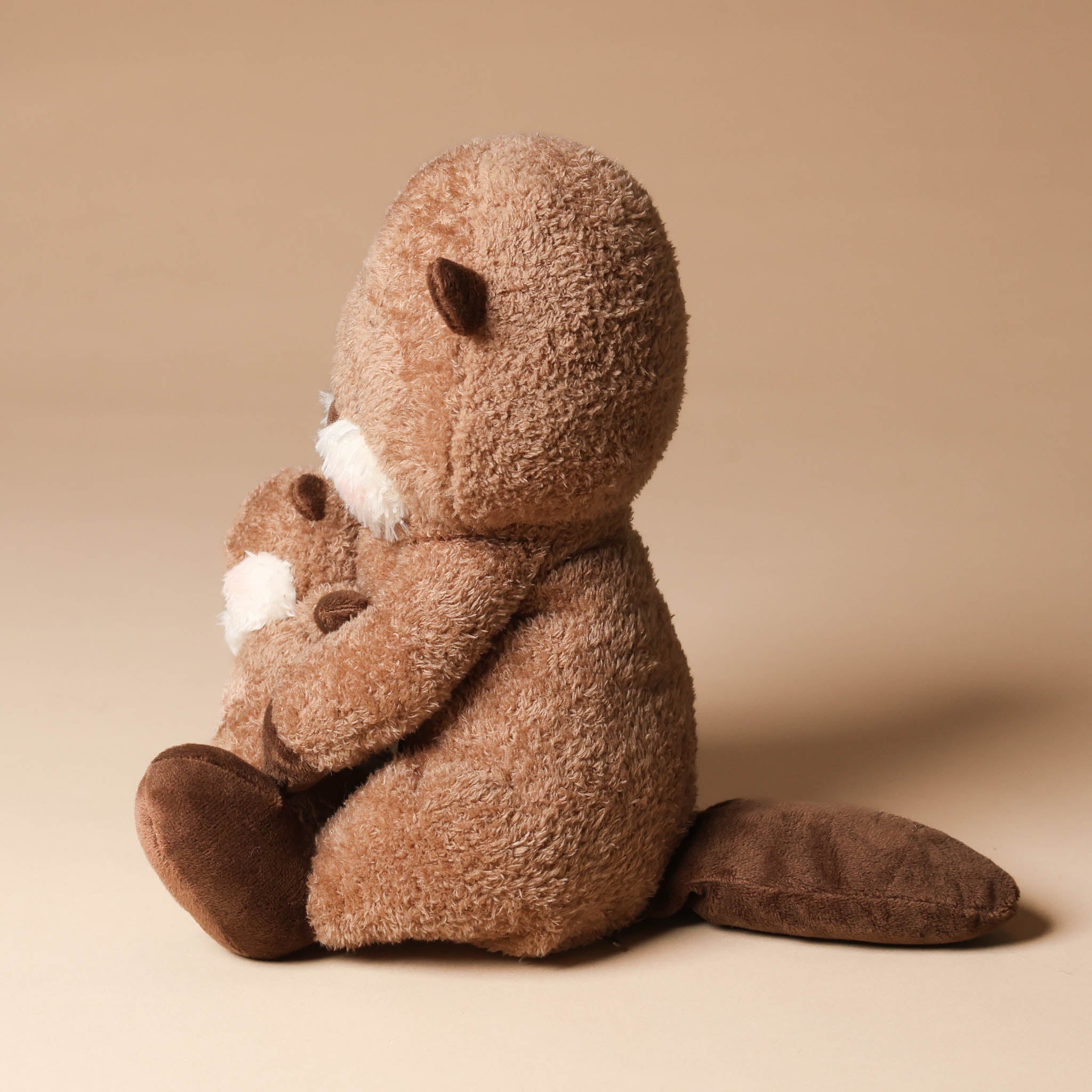 Plush toy ollie-otter-and-baby sitting on a beige background