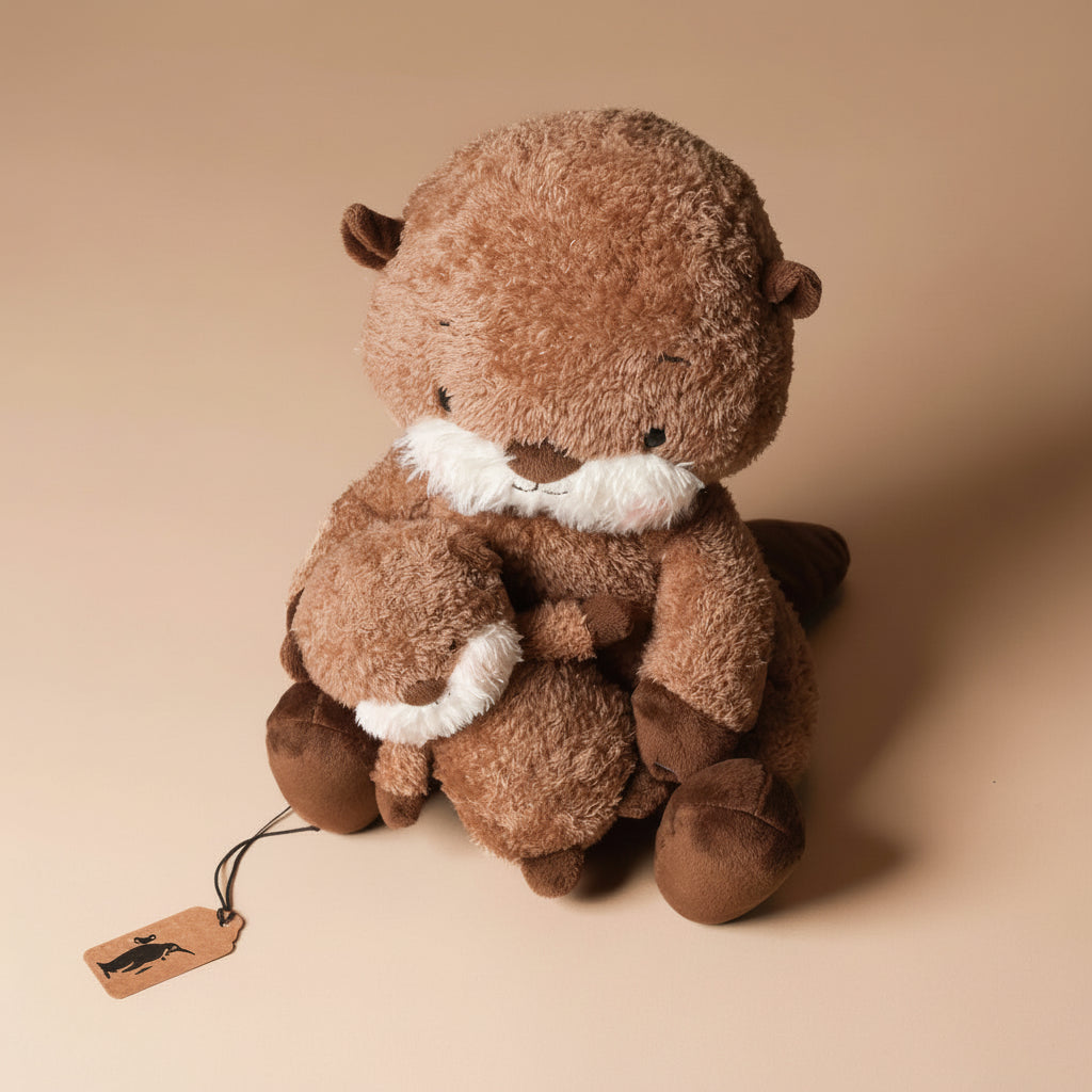 Plush toy ollie-otter-and-baby sitting on a beige background