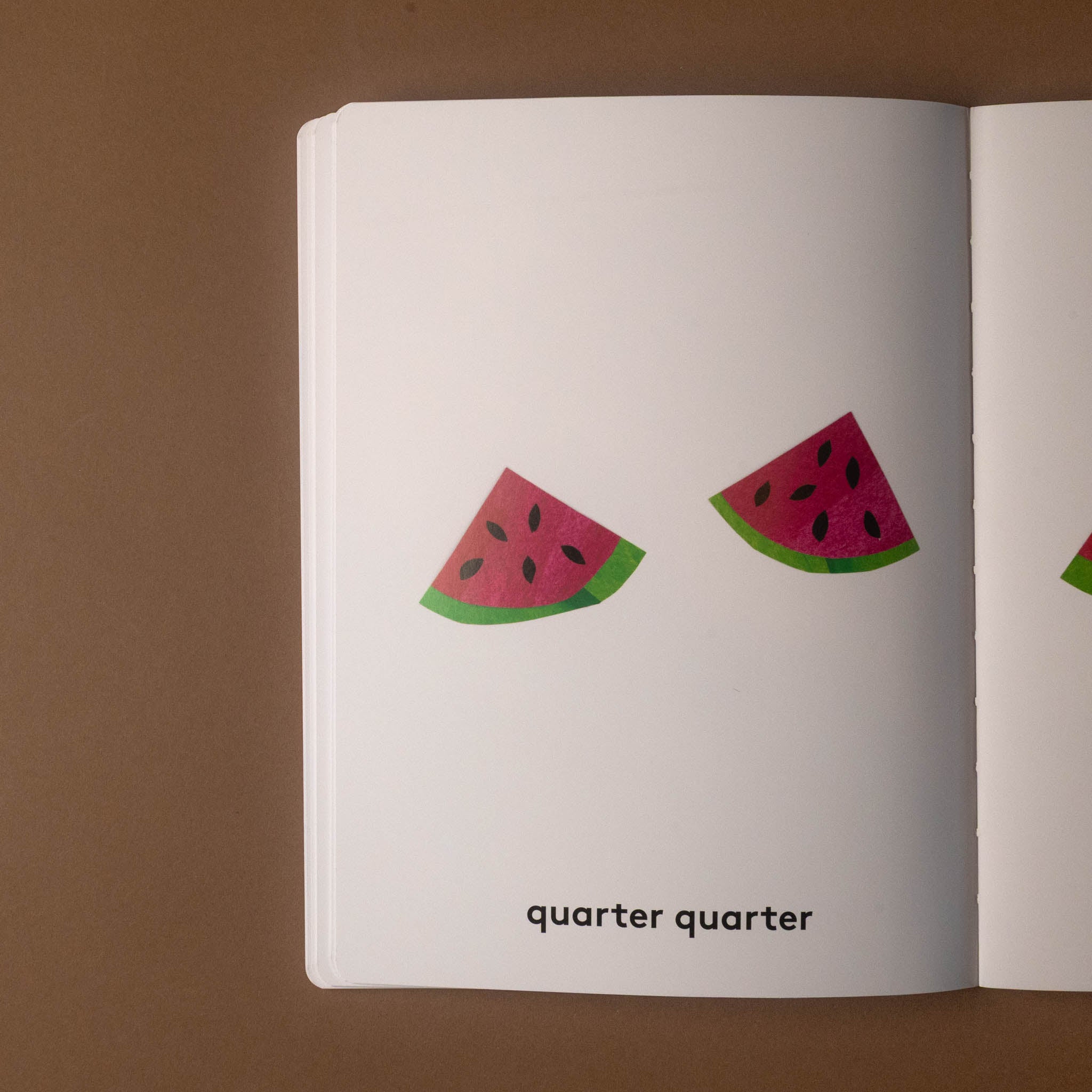 Open one-whole-hippopotamus book with watermelon slice illustrations and 'quarter quarter' text on a brown background