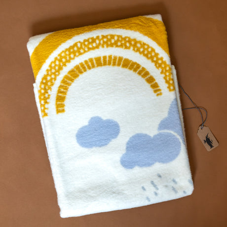 organic-cotton-baby-blanket-yellow-rainbow-and-sun-with-blue-grey-clouds-and-raindrops-on-cream-backdrop