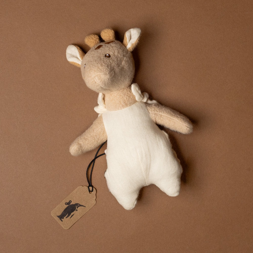 organic-cotton-leonie-giraffe-with-pocket- Stuffed giraffe toy with a tag on a brown background