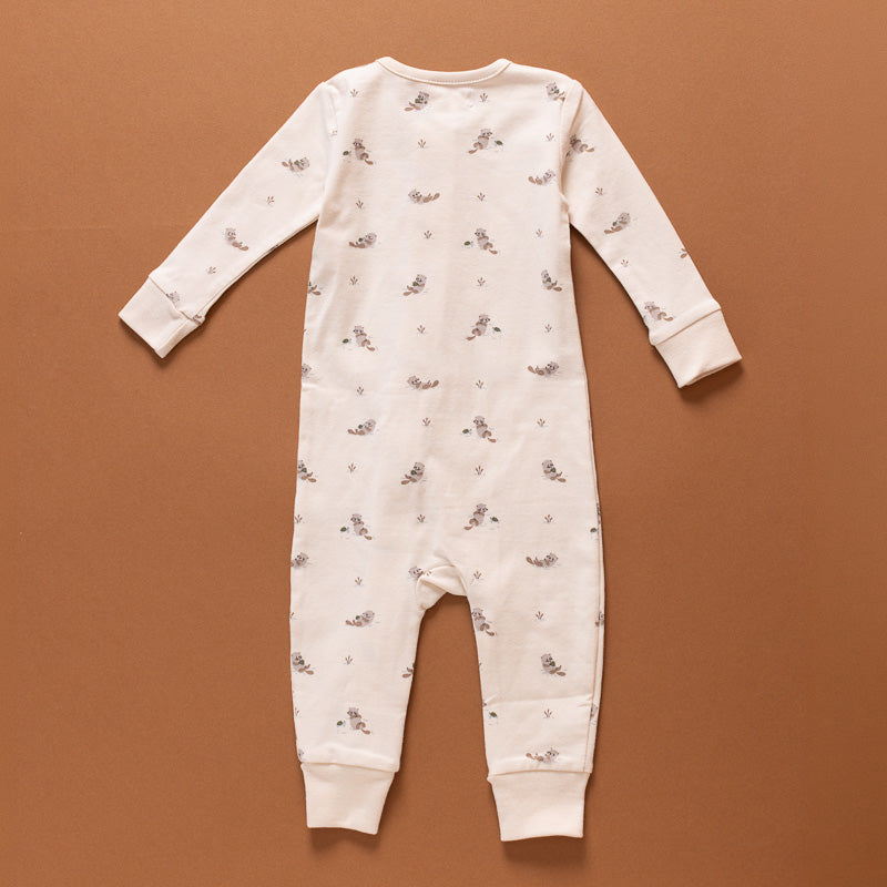 A baby long-sleeve footless one-piece jumpsuit in cream with a small brown and gray animal print, laid flat on a solid brown background.