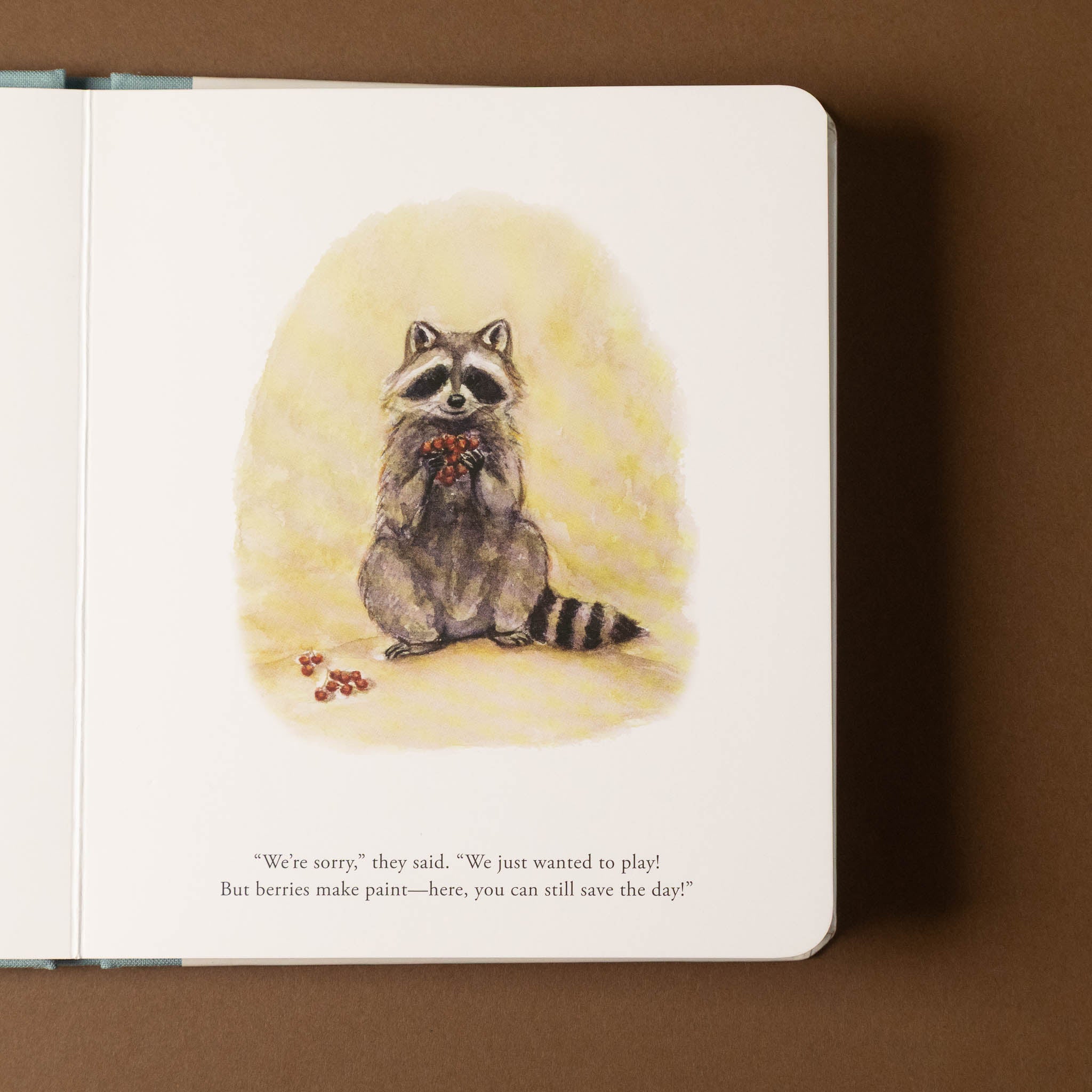 Illustrated our-little-adventures-at-easter-board-book raccoon on a notebook page with a brown background