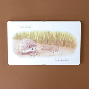 a-hedgehog-atop-a-bear-print-in-the-muddy-grass--with-text