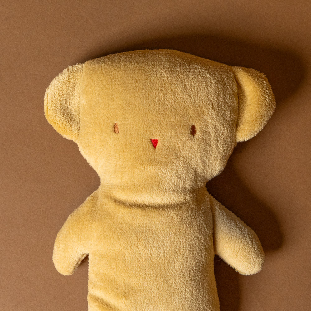 pancake-teddy bear stuffed-animal with a tag on a brown background