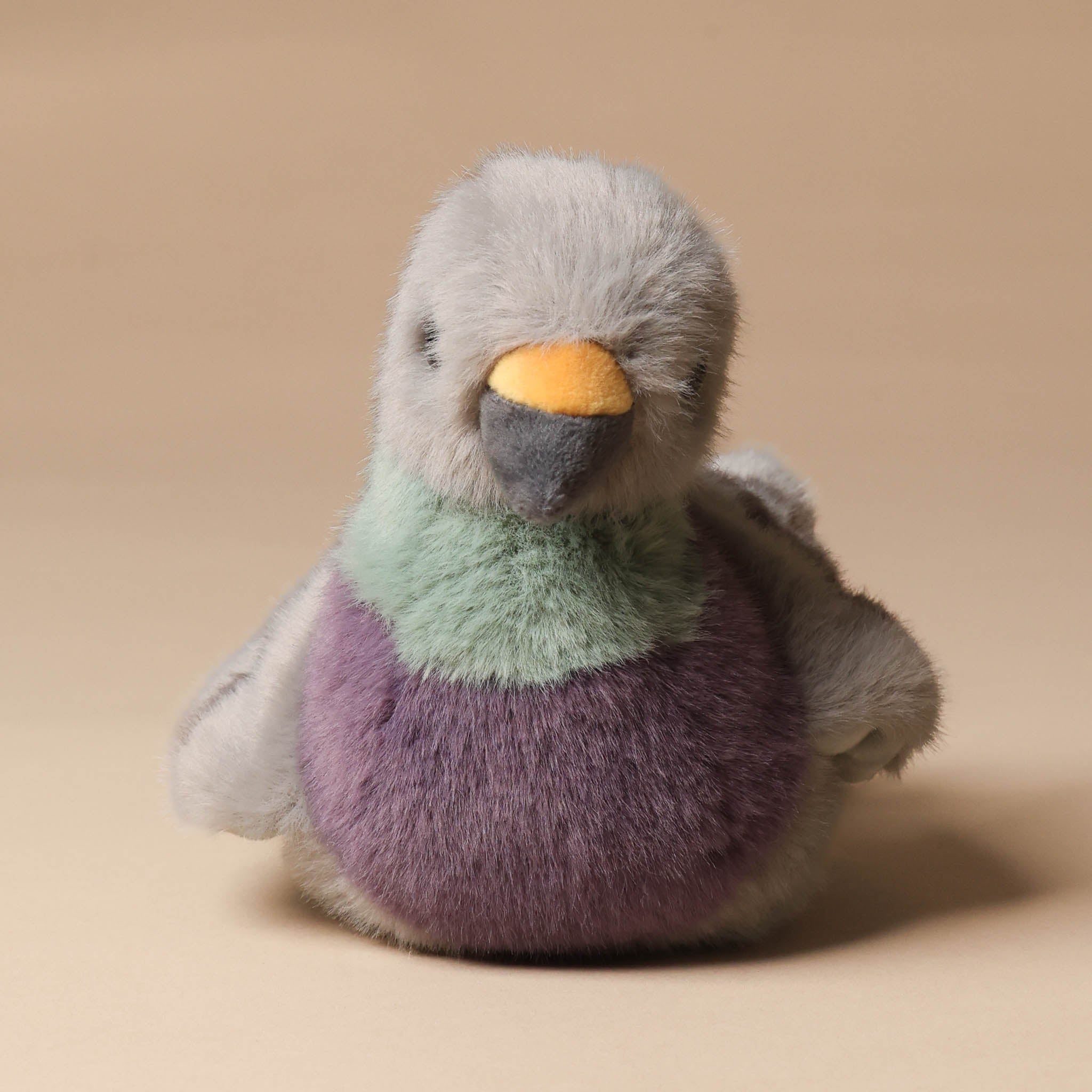Stuffed toy penguin with a gradient from gray to purple on a beige background