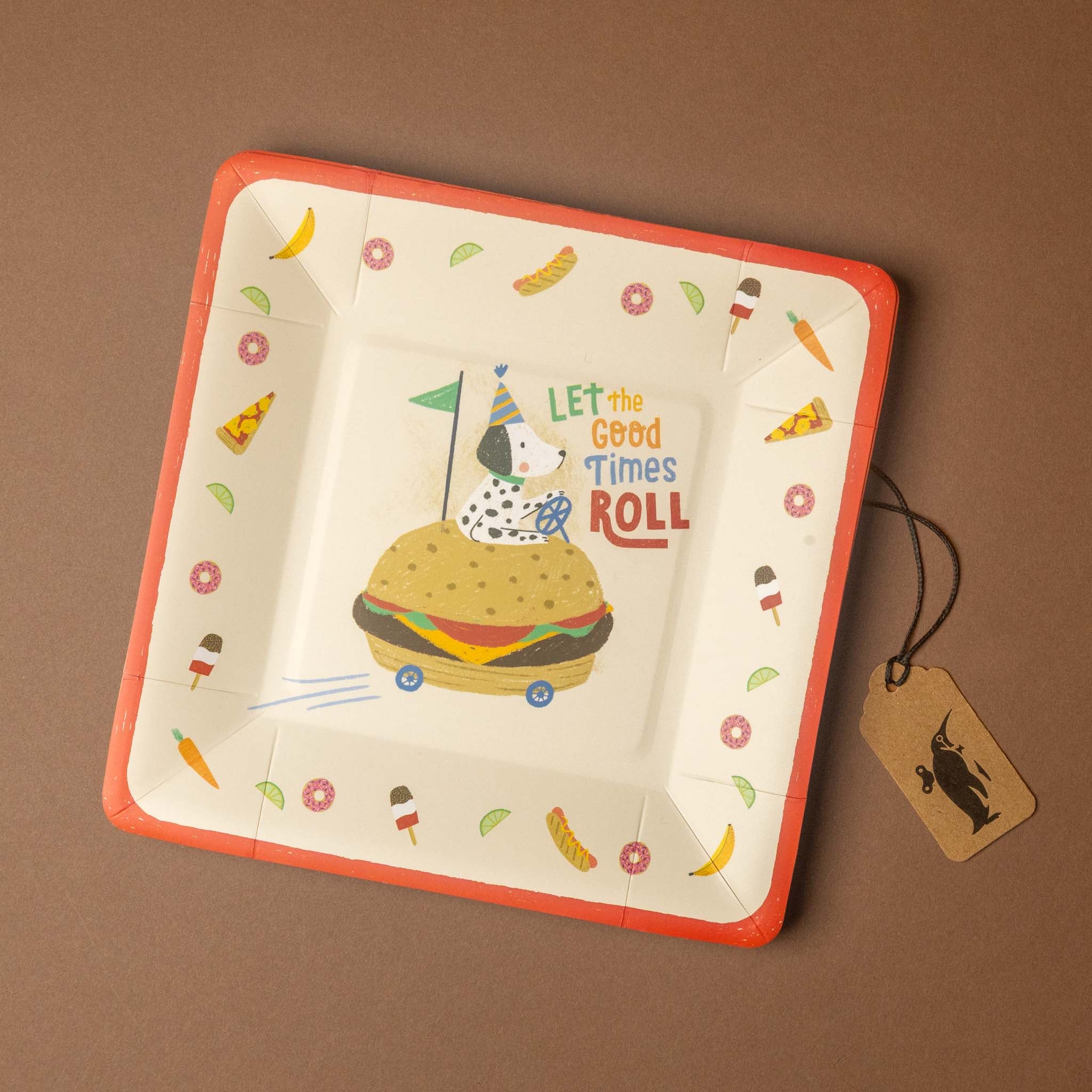 A square white paper party plate with a bright orange rim, featuring a cartoon dog riding a hamburger and the text 'LET the Good Times ROLL' in the center. The plate is decorated with small colorful illustrations of ice cream cones, bananas, and flowers.