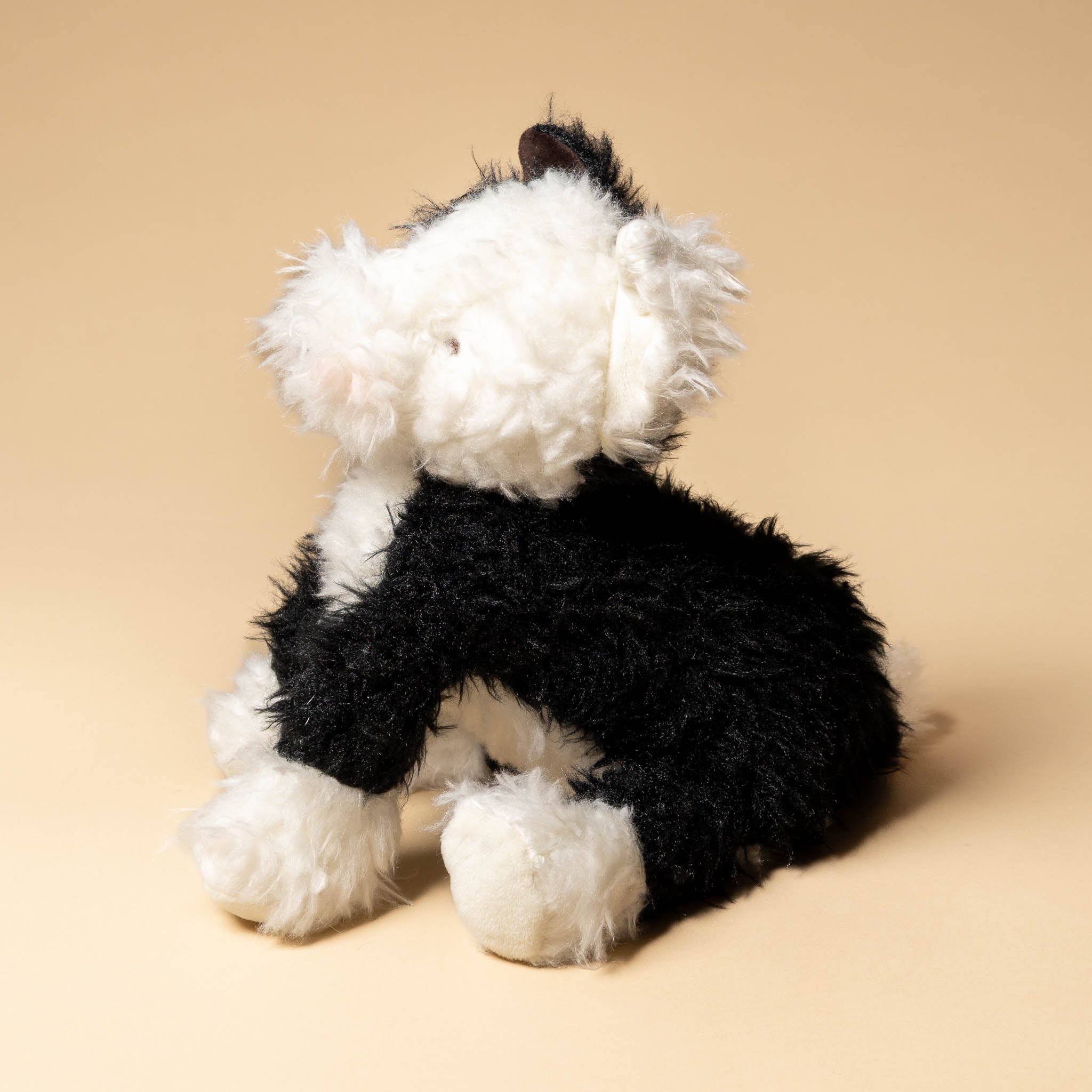 pepper-the-farm-dog Black and white plush dog toy on a beige background